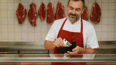 Ein Fleischer in Arbeitskleidung steckt einen 100-Euro-Schein in sein Geldtascherl – ein symbolisches Motiv für den aktuellen Gehaltsabschluss 2025 und die bevorstehende Kaufkraftsicherungsprämie. © KI-generiertes Symbolbild / ChatGPT Image Gen